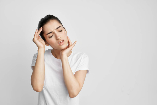 Woman in white t-shirt holding her head dissatisfied with health problems - Photo, Image