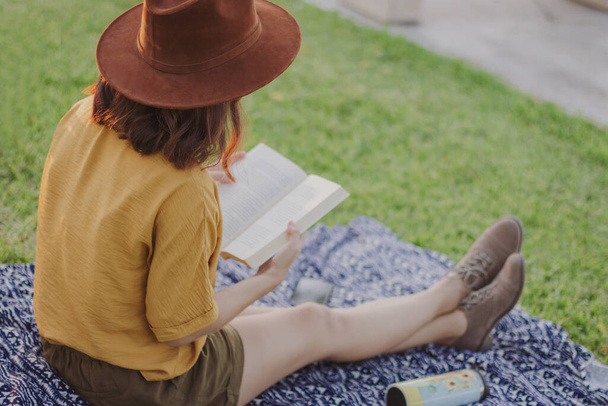 Nuori nainen yllään hattu käsittelyssä kirjan puistossa valikoiva keskittyä - Valokuva, kuva