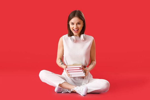 Young woman with books and headphones on color background - Photo, Image