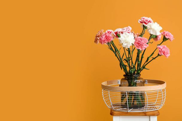 Váza s karafiáty květiny na stole v blízkosti barevné stěny - Fotografie, Obrázek
