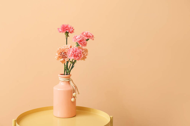 Vase with beautiful carnation flowers on table near color wall - Fotografie, Obrázek