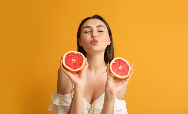 Young woman with juicy grapefruit on color background - Foto, Bild
