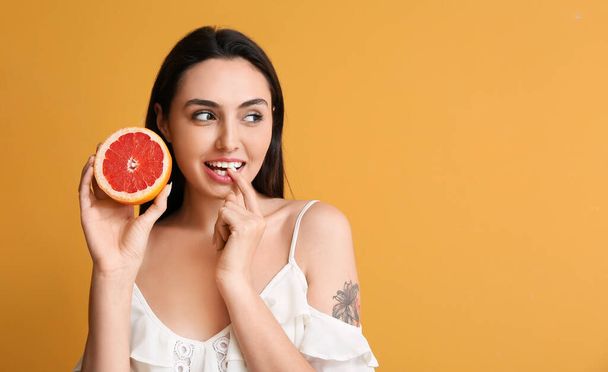 junge Frau mit saftigen Grapefruit auf farbigem Hintergrund - Foto, Bild