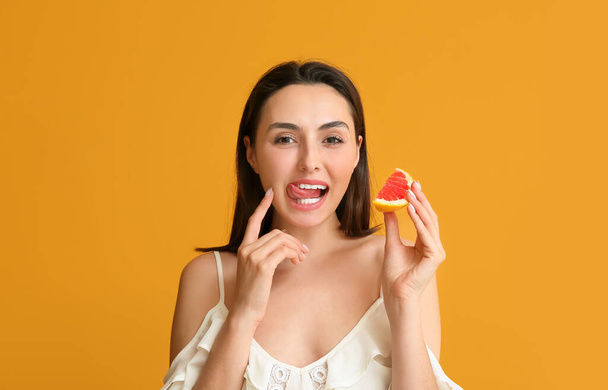 Mladá žena s šťavnatým grapefruitem na barevném pozadí - Fotografie, Obrázek