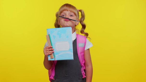 Funny linda niña de la escuela primaria haciendo juguetonas expresiones faciales tontas jugando con la pluma - Foto, Imagen