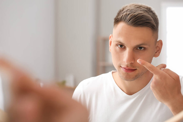 Young man putting in contact lenses at home - Foto, Imagen
