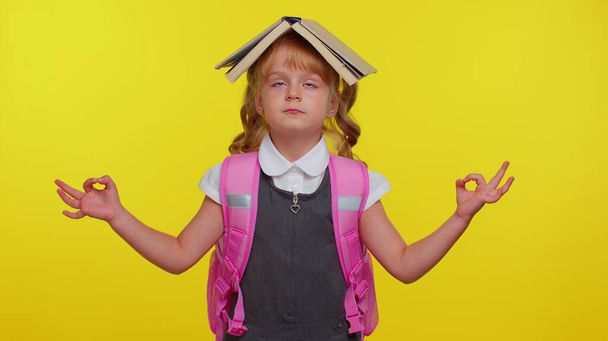 Девочка-подросток в школьной форме надевает книгу на голову, медитирует, расслабляется с сосредоточенными мыслями - Фото, изображение