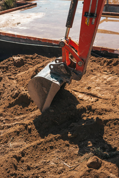 Екскаваторна лопатка копає на землі на будівельному майданчику
 - Фото, зображення