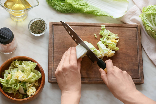 Woman cutting fresh chinese cabbage on table - Foto, Bild