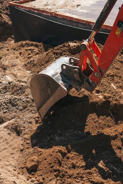 Pala excavadora excavando en la suciedad en un sitio de construcción - Foto, Imagen