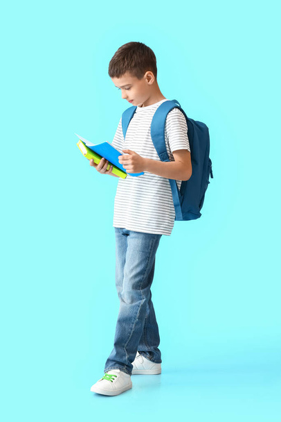 Маленький школьник с блокнотами на цветном фоне - Фото, изображение
