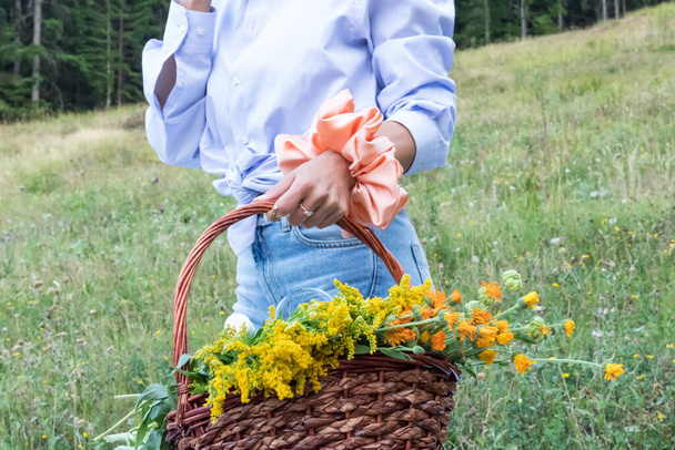 A view of a female carrying a basket of flowers with a beautiful scrunchy on her hand in the filed - Foto, immagini