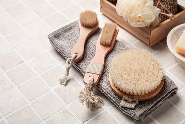 Different body brushes and bath supplies in light tile background - Zdjęcie, obraz