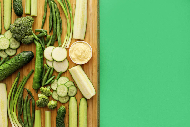 緑の野菜と色の背景にソースとボウルが異なるボード - 写真・画像