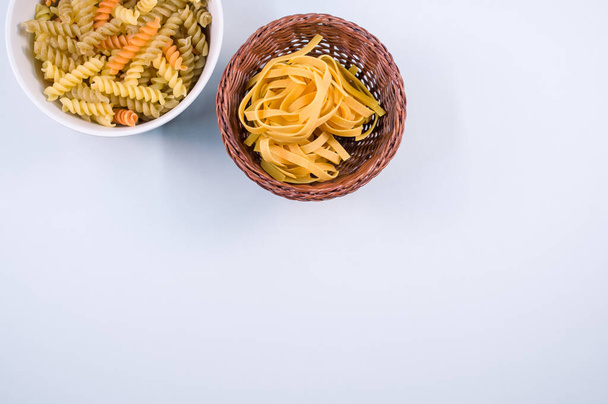 A top view of tri-color rotini and fettuccine pasta on a bowl isolated on white background - Foto, Imagem