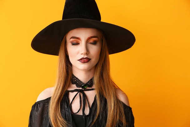 Hermosa mujer vestida de bruja para Halloween sobre fondo de color - Foto, imagen