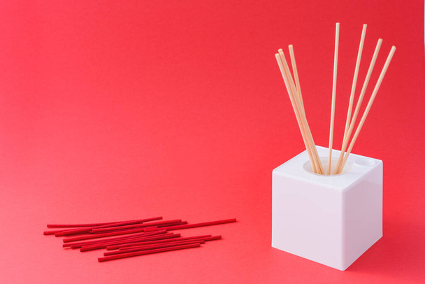 A white cube box with incense sticks on a red background - Φωτογραφία, εικόνα