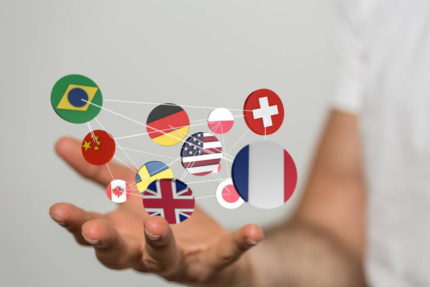 A hand holding connected floating icons of different country flags - Foto, Imagem