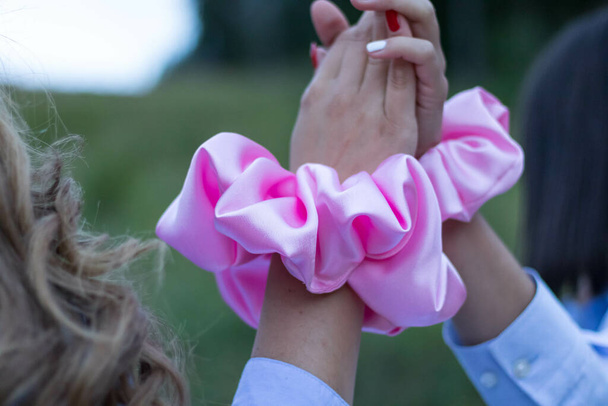 A back view of females with beautiful trendy scrunchies on their hands giving a high five - Фото, изображение