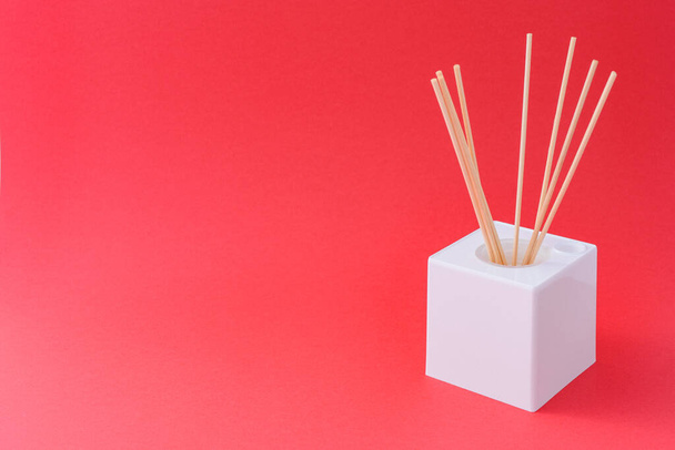 A white cube box with incense sticks on a red background - Fotografie, Obrázek