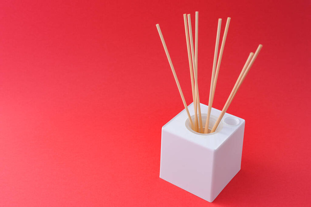 A white cube box with incense sticks on a red background - Foto, Bild