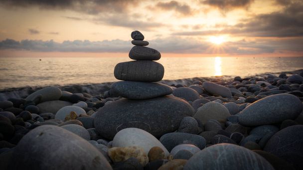 日没のビーチで禅の石のスタックは、美しい海の風景です。休息の概念として石塔の製. - 写真・画像