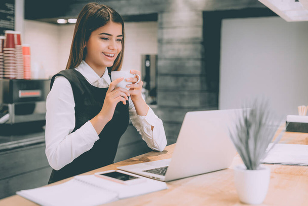Счастливая деловая женщина пьет кофе на рабочем столе - Фото, изображение