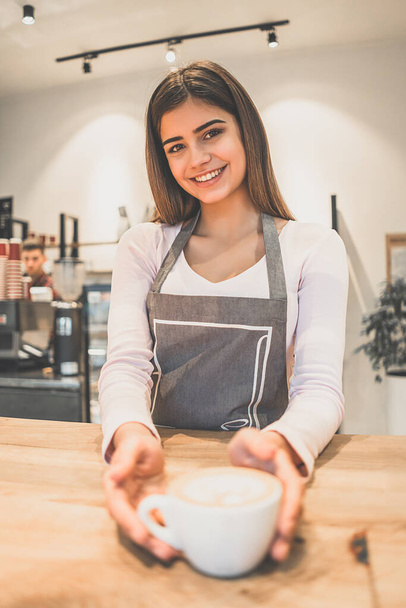 La camarera sonriente sosteniendo una taza de café en un café - Foto, Imagen