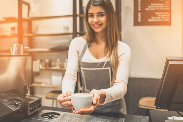 Szczęśliwa kelnerka trzymająca filiżankę kawy - Zdjęcie, obraz