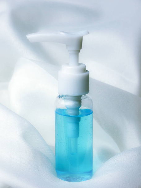 malý modrý alkohol gel čerpací láhev na bílém textilním pozadí - Fotografie, Obrázek