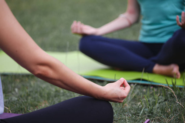 Close up hands. Happy girls doing yoga in the park on the grass. Healthy and Yoga Concep - Photo, image