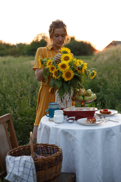 garden and still life. tea party in the garden - girl and bouquet with sunflowers on the tabl - Zdjęcie, obraz