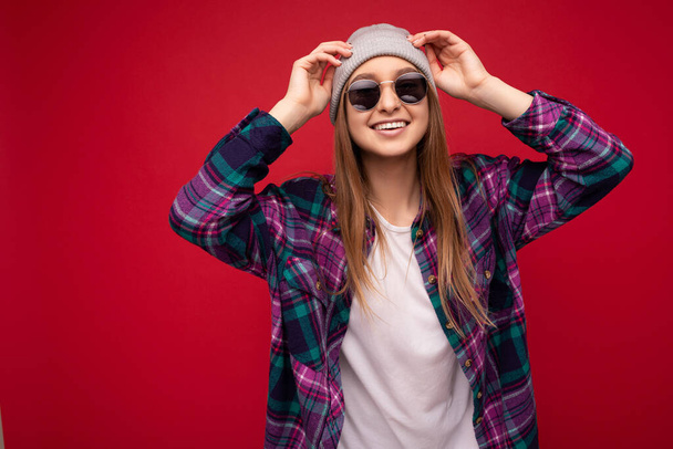Photo shot of beautiful positive young brunette woman wearing summer casual clothes and stylish sunglasses isolated over colorful background wall looking at camera - 写真・画像