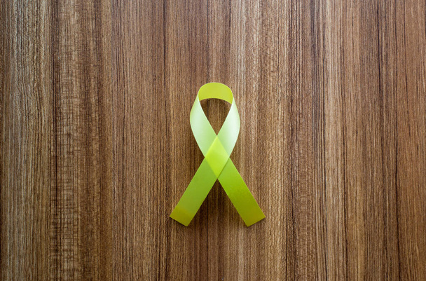 Yellow ribbon on wooden background,Suicide prevention,Cancer disease awareness concept,Top vie - Photo, Image