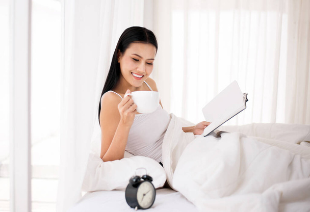 Happy beautiful asian woman drinking coffee and reading book on bed,Happy and smiling,Positive thinking,Relax time - Foto, immagini