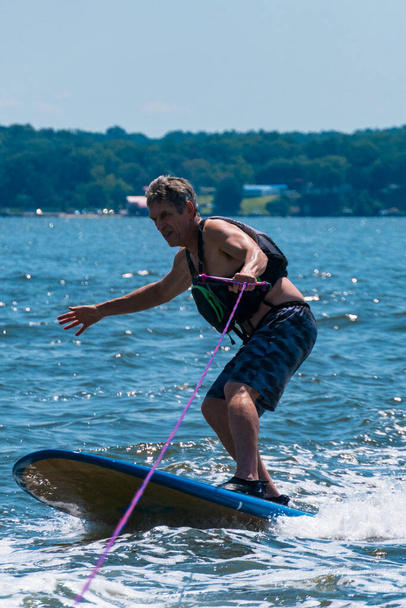 Broomes Island, Maryland Un hombre de esquí acuático mientras está de pie en una tabla de paddle. - Foto, imagen