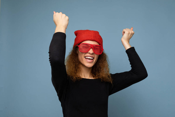 Foto-Foto von schönen glücklich lächelnde junge dunkelblonde Frau trägt lässige Kleidung rotes Kopftuch und stilvolle Sonnenbrille isoliert über bunten Hintergrund Blick in die Kamera - Foto, Bild