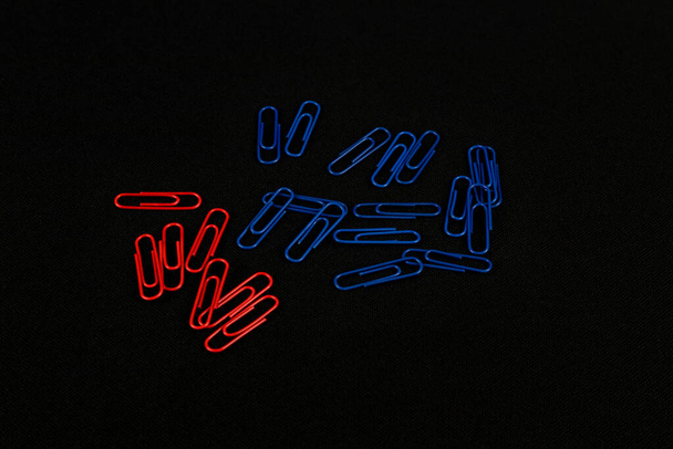 Some red and blue paper clips on a black background - Foto, immagini