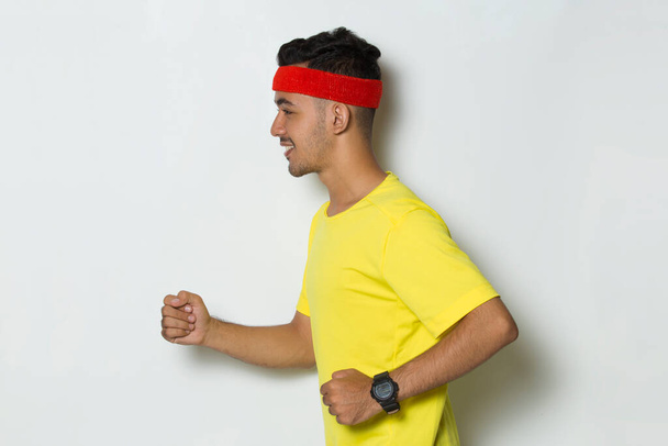 jovem homem desportivo vestido de tshirt amarela correndo em fundo branco - Foto, Imagem