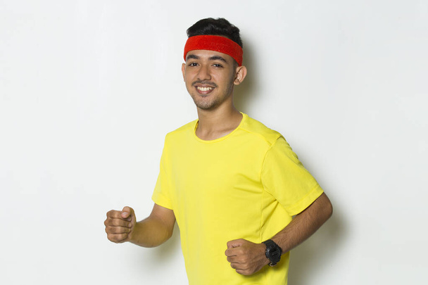 junger sportlicher Mann in gelbem T-Shirt läuft auf weißem Hintergrund - Foto, Bild