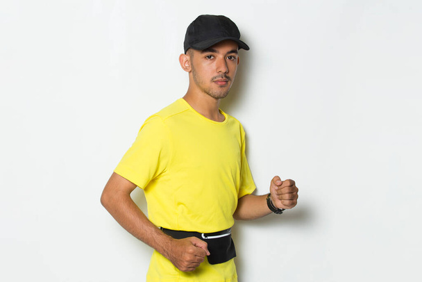 nuori urheilullinen mies pukeutunut keltainen t paita käynnissä valkoinen tausta - Valokuva, kuva