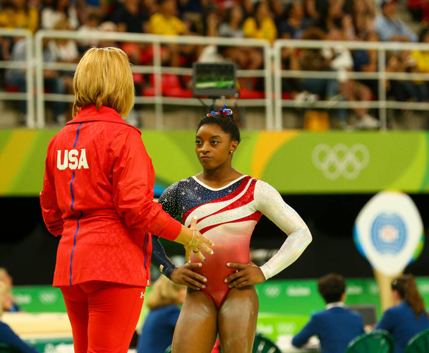 RIO DE JANEIRO, BRAZIL - AUGUST 9, 2016: Olympic champion Simone Biles of United States with coach during team women's all-around gymnastics competition at Rio 2016 Olympic Games at Rio Olympic Arena - Valokuva, kuva