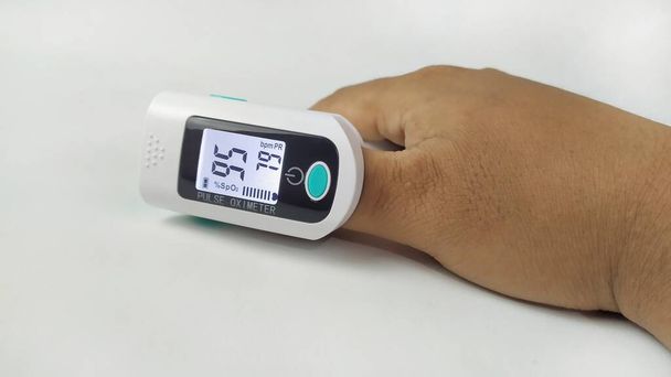 Oxímetro de pulso digital que se utiliza en la mano para comprobar la saturación de oxígeno del coronavirus o covid 19 pacientes sobre fondo blanco - Foto, imagen