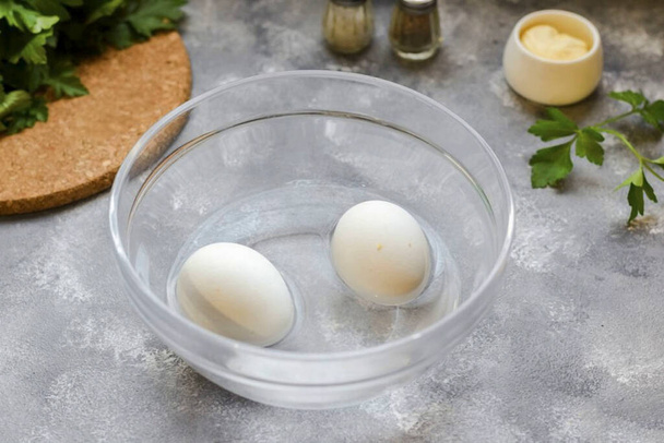 Hervir los huevos de pollo durante 10 minutos, luego enfriar en agua fría. - Foto, Imagen