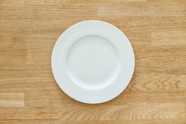 Empty white plate on wooden table - Photo, Image