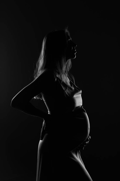 silhueta de mulher grávida em um fundo preto - Foto, Imagem