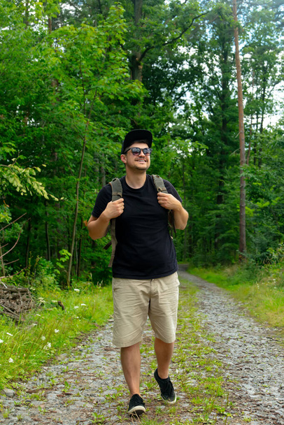 Beyaz adam yaz zamanı ormanda yolda yürüyor. - Fotoğraf, Görsel