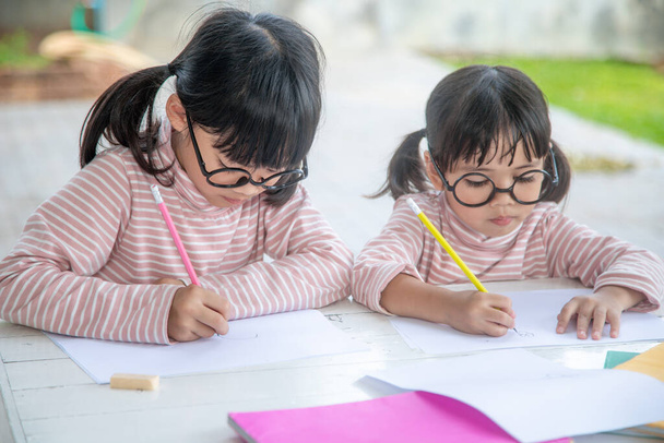 Kaksi aasialaista lasta tekemässä läksyjä yhdessä kotona - Valokuva, kuva