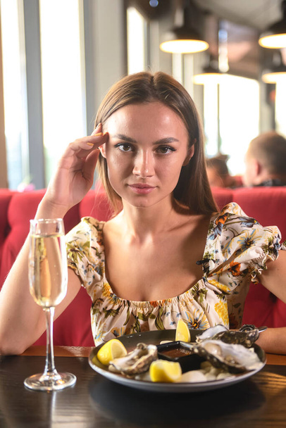 Beautiful sexy brunette woman in expensive restaurant eating oysters and drinking champagne. Eat out concept, oysters and champagne in a restaurant, eat and drink. - Foto, Imagem