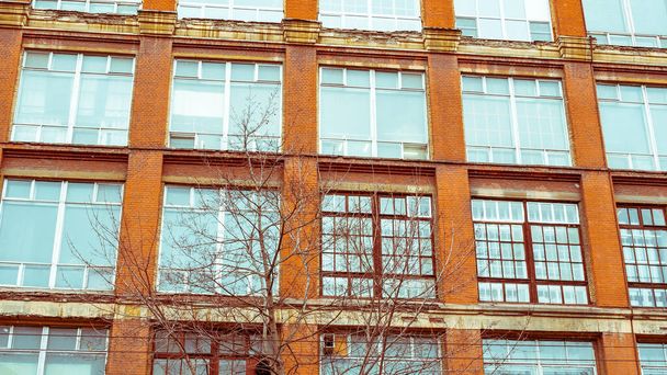 Ο τοίχος ενός παλιού βιομηχανικού κτιρίου με μεγάλα παράθυρα. Βιομηχανική αρχιτεκτονική των αρχών του 20ου αιώνα. - Φωτογραφία, εικόνα